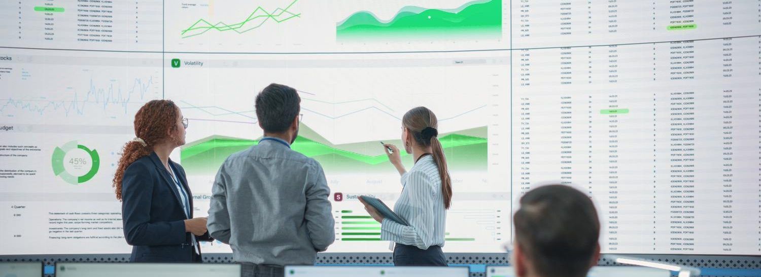 Drei Personen stehen vor großen Bildschirmen mit Datenvisualisierungen und Diagrammen, die Datenqualität und Governance symbolisieren.